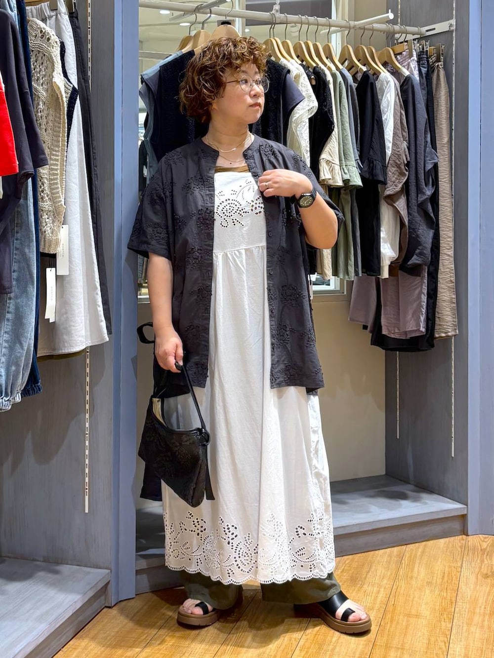 ブラック系のショルダーバッグ、ブラック系のサンダル、ブラウン系のタンクトップを着用したレディースの夏コーディネートの2枚目の写真