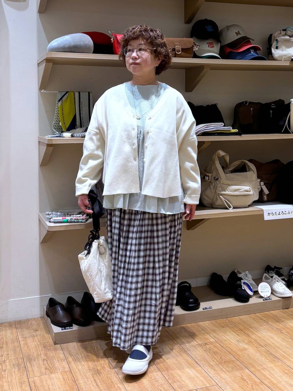 ベージュ系のショルダーバッグ、ブラウン系のスカート、ベージュ系のカーディガン/ボレロを着用したレディースの冬コーディネートの4枚目の写真