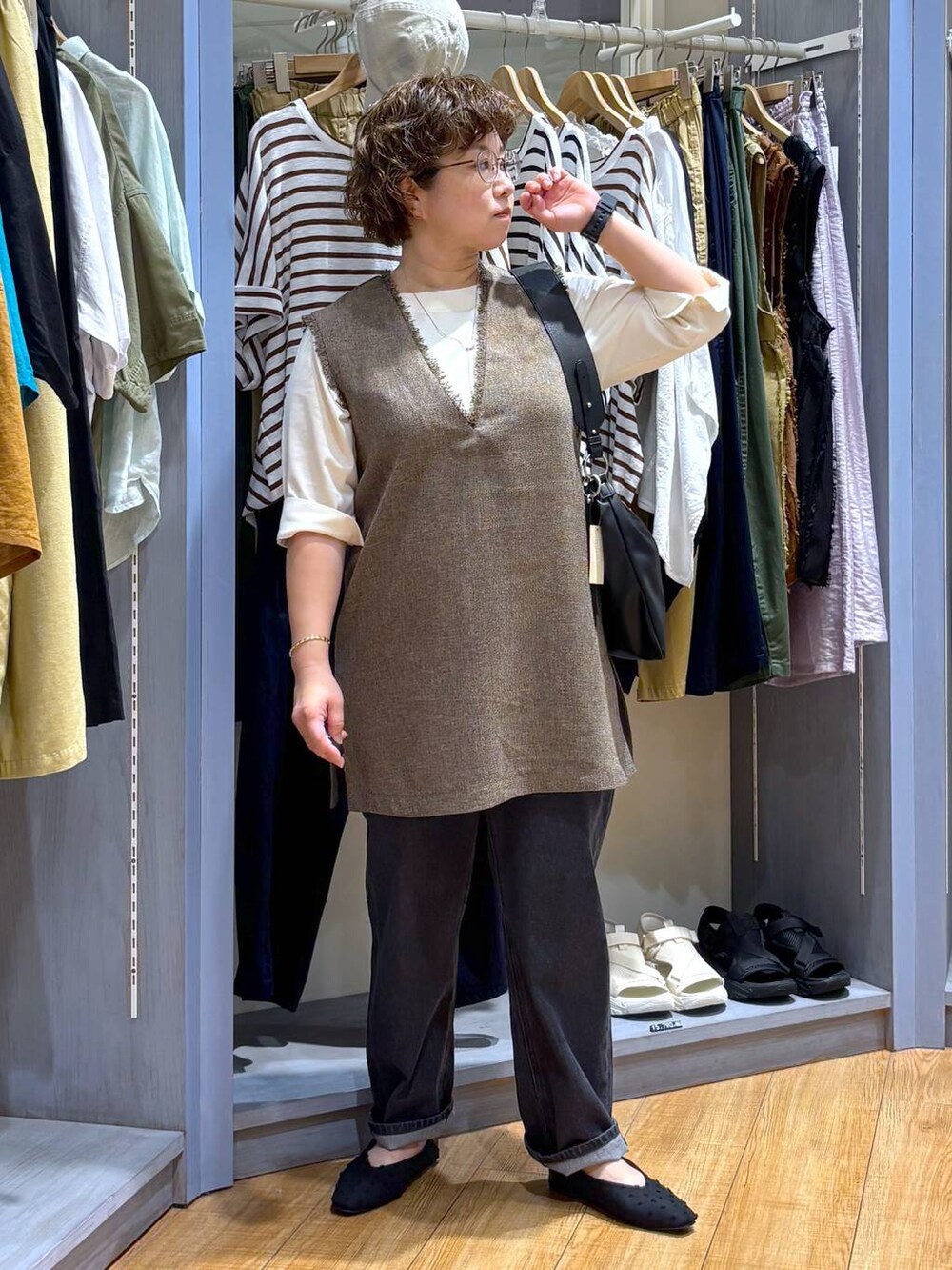 ブラック系のデニムパンツ、ブラウン系のワンピース、ブラック系のショルダーバッグを着用したレディースの夏コーディネートの3枚目の写真