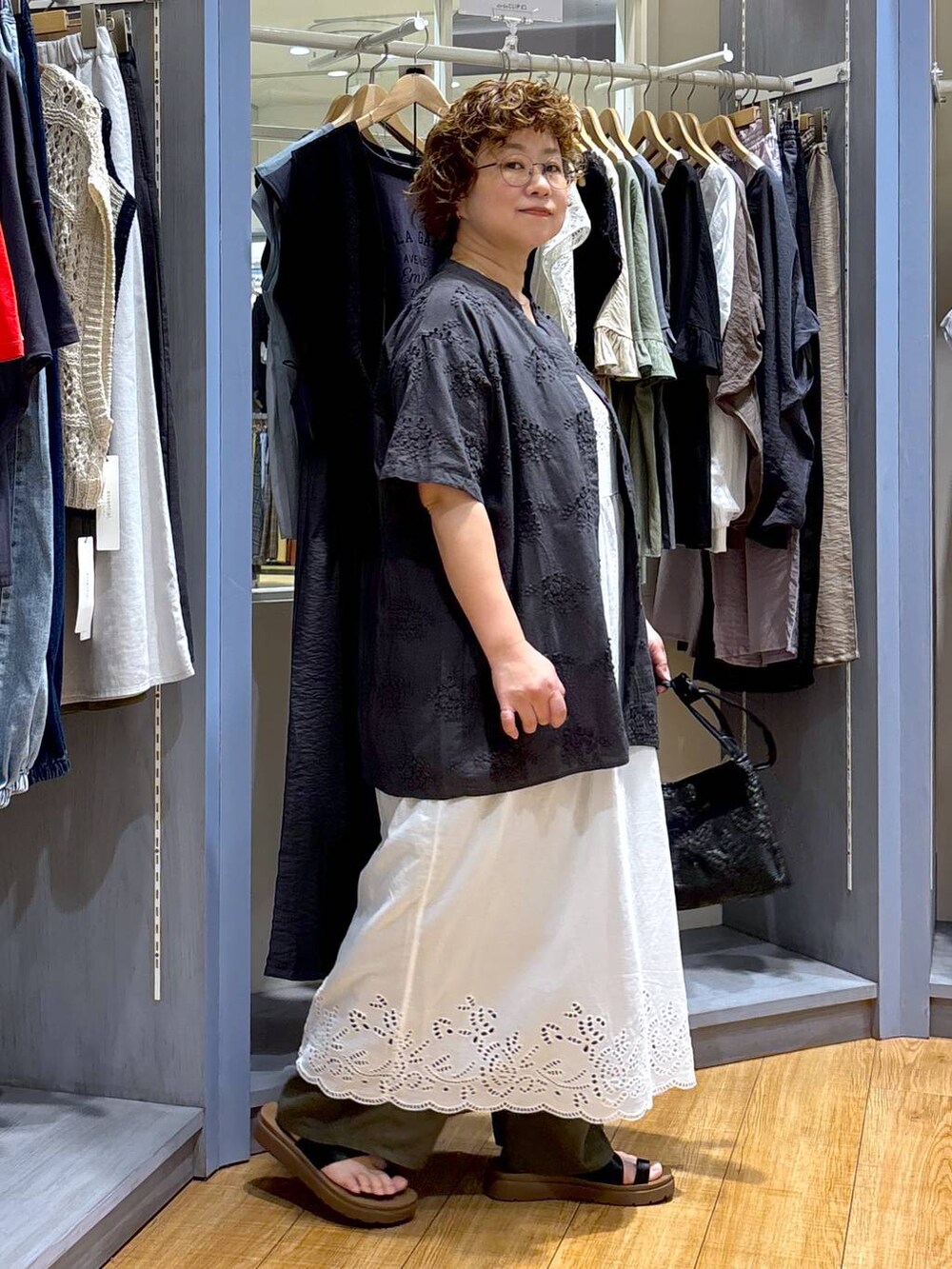 ブラック系のショルダーバッグ、ブラック系のサンダル、ブラウン系のタンクトップを着用したレディースの夏コーディネートの3枚目の写真