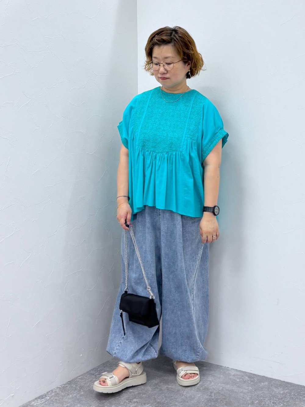 ホワイト系のサンダル、ブルー系のデニムパンツ、その他のネックレスを着用したレディースの夏コーディネートの2枚目の写真