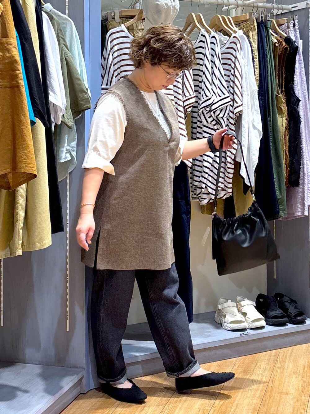 ブラック系のデニムパンツ、ブラウン系のワンピース、ブラック系のショルダーバッグを着用したレディースの夏コーディネートの4枚目の写真