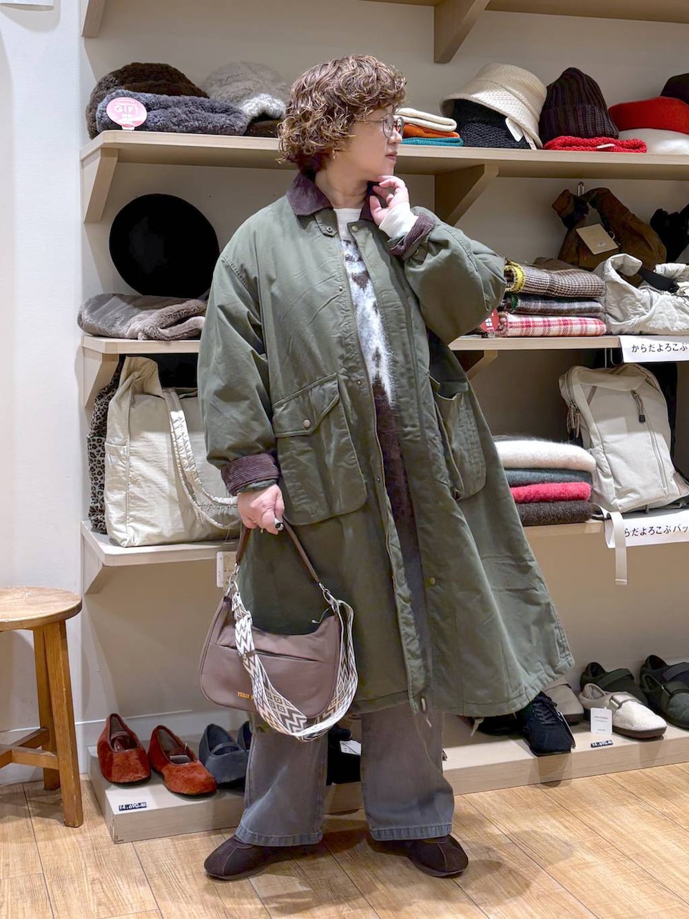 グレー系のデニムパンツ、グリーン系のモッズコート、ブラウン系のショルダーバッグを着用したレディースの秋コーディネートの2枚目の写真