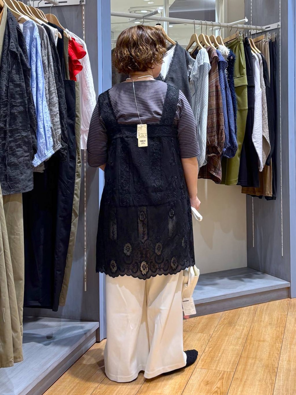 ホワイト系のショルダーバッグ、ブラック系のチュニック、ブラック系のパンプスを着用したレディースの夏コーディネートの5枚目の写真