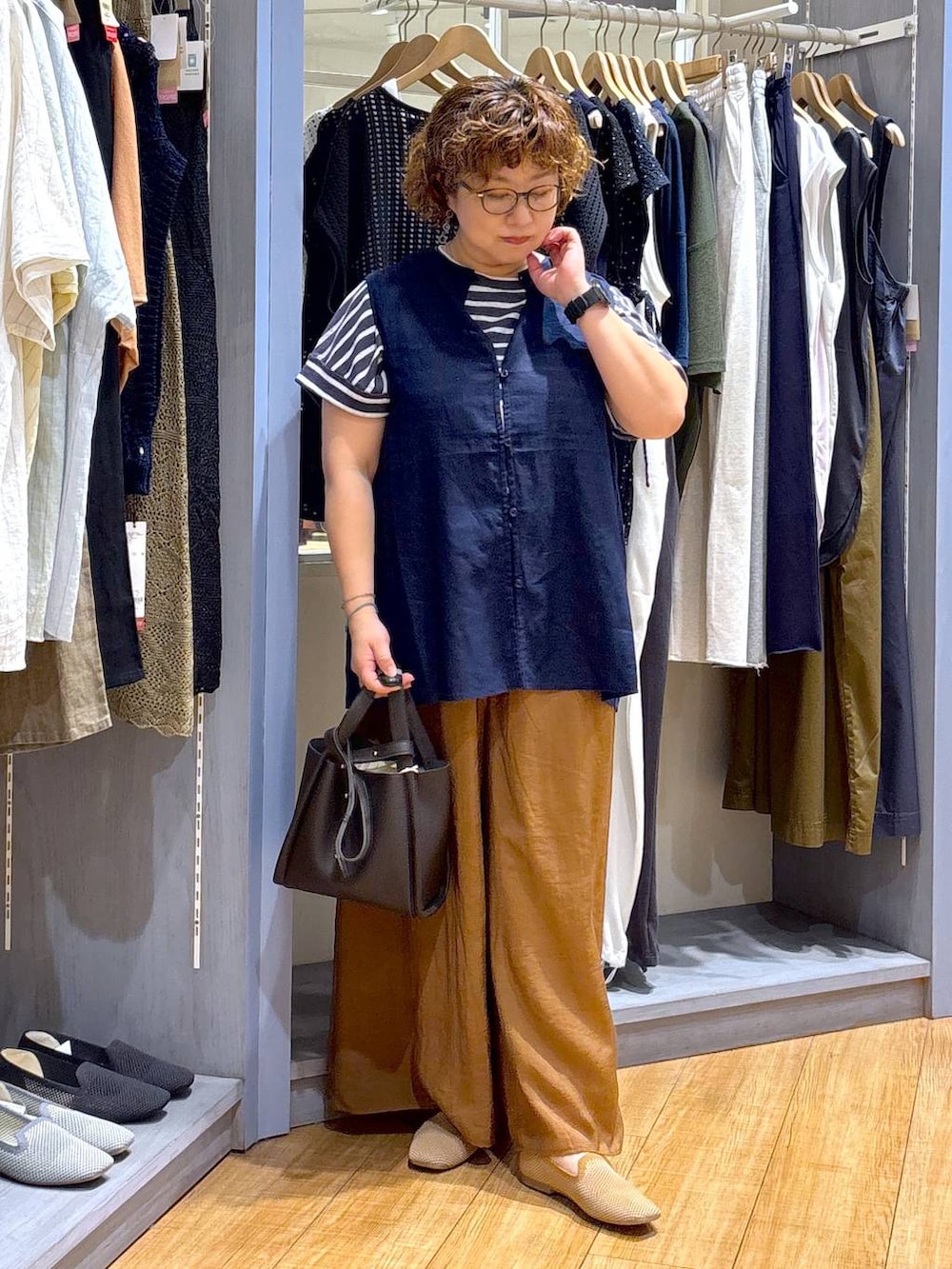 ブルー系のシャツ/ブラウス、ベージュ系のパンプス、ブラウン系のショルダーバッグを着用したレディースの夏コーディネートの2枚目の写真