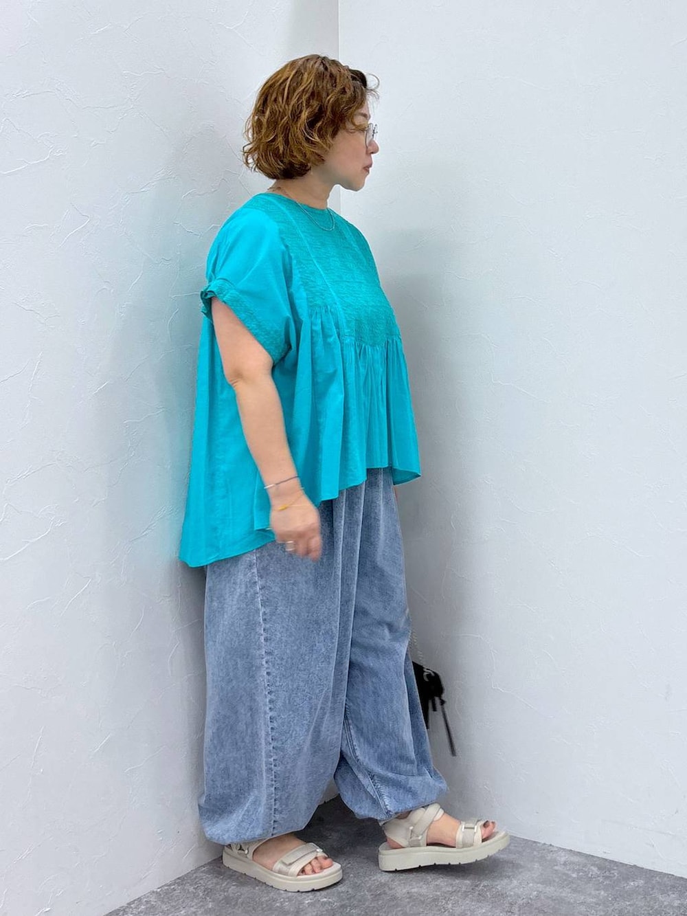 ホワイト系のサンダル、ブルー系のデニムパンツ、その他のネックレスを着用したレディースの夏コーディネートの4枚目の写真