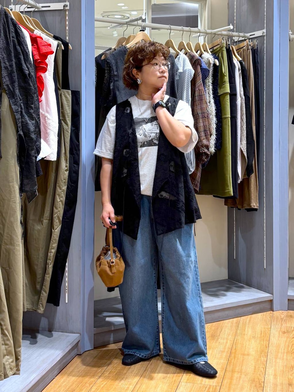 ブルー系のデニムパンツ、ブラウン系のショルダーバッグ、ブラック系のパンプスを着用したレディースの秋コーディネートの3枚目の写真