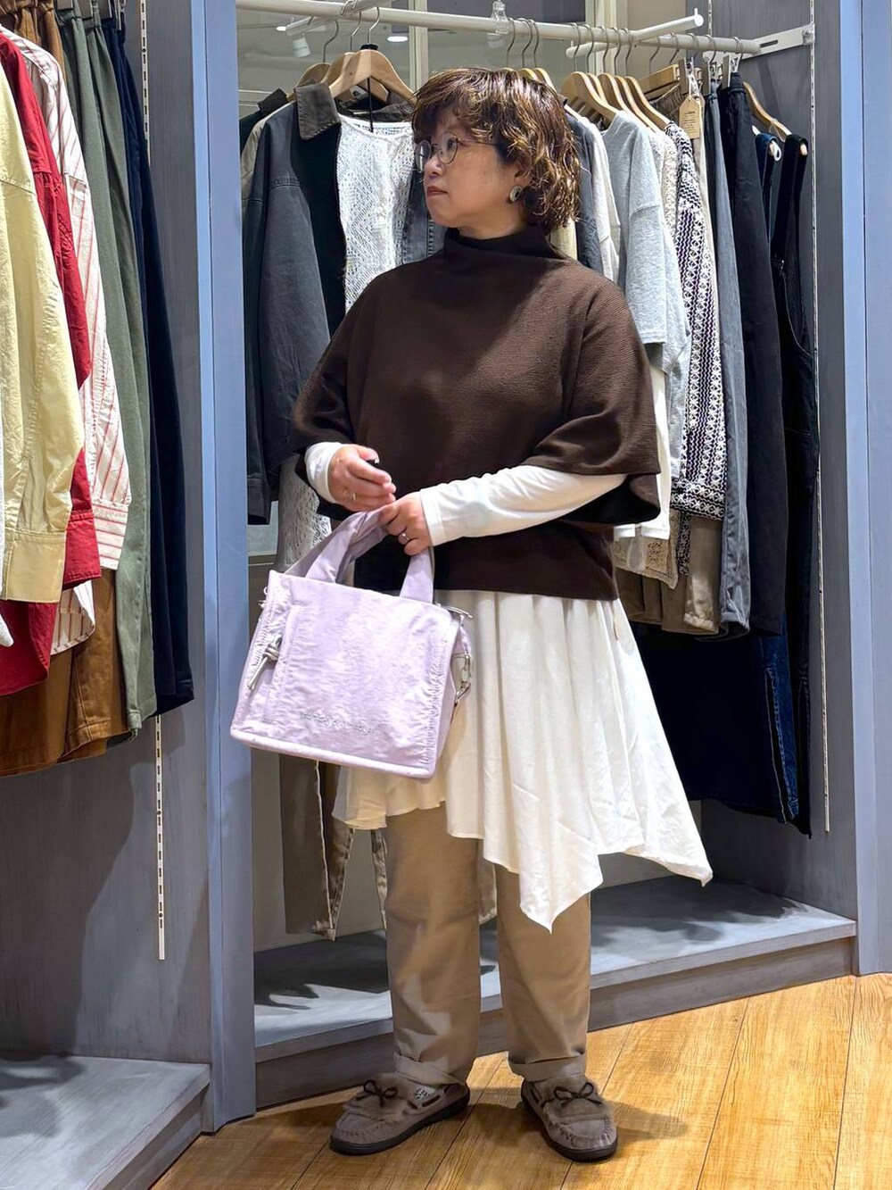 グレー系のモカシン/デッキシューズ、ブラウン系のベスト、ベージュ系のチュニックを着用したレディースの秋コーディネートの3枚目の写真