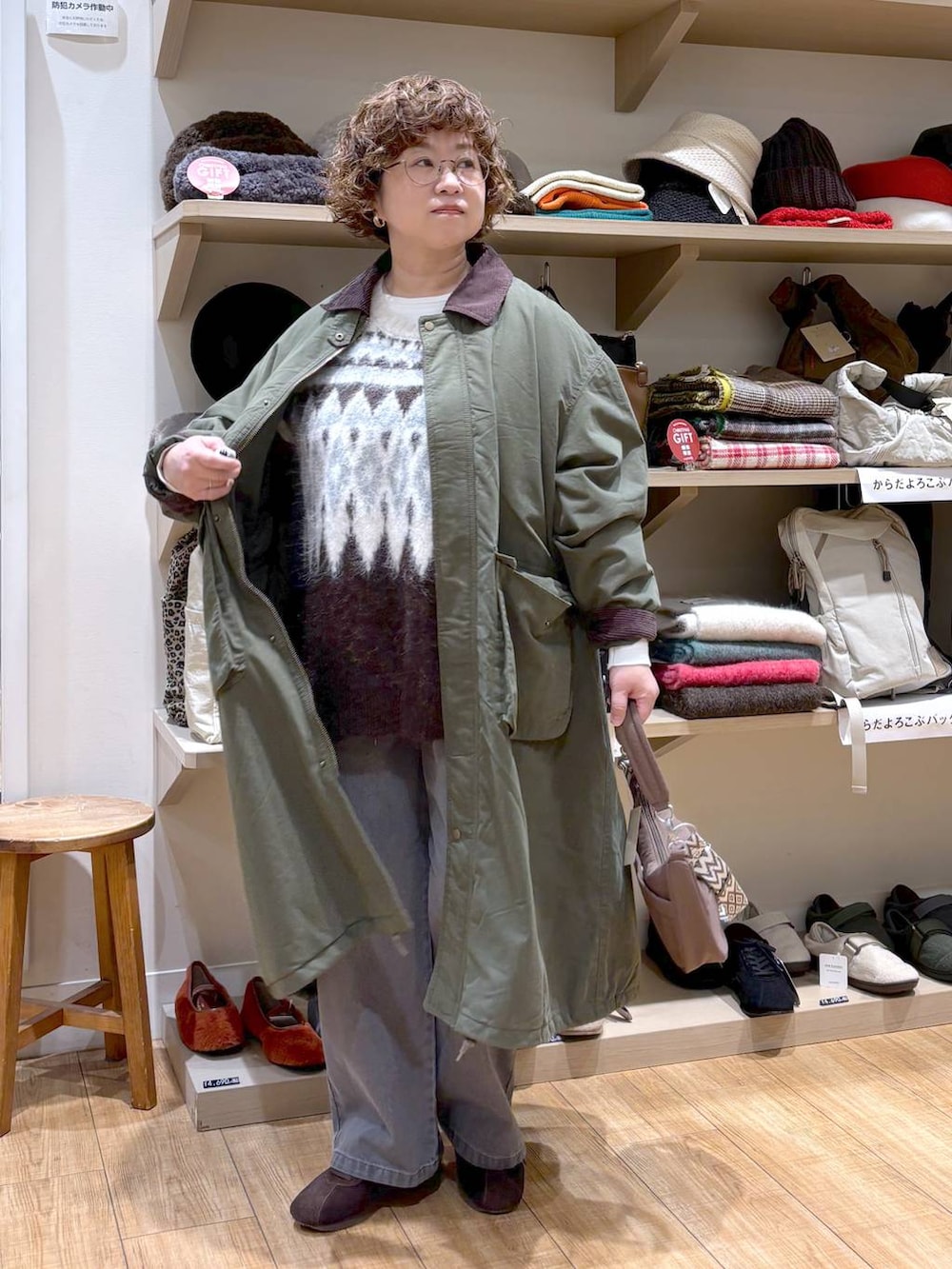 グレー系のデニムパンツ、グリーン系のモッズコート、ブラウン系のショルダーバッグを着用したレディースの秋コーディネートの3枚目の写真