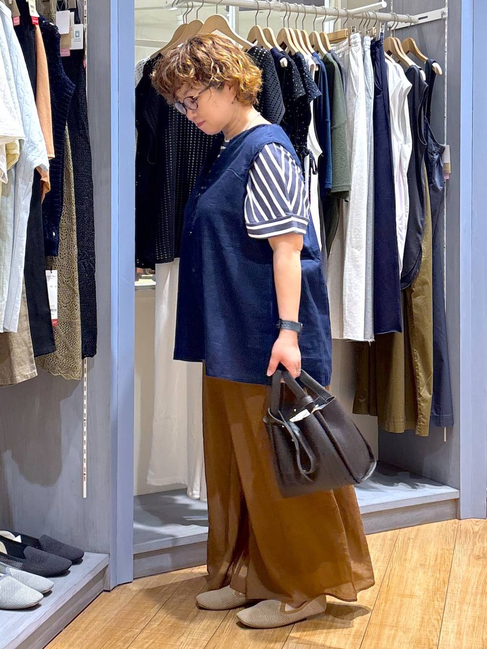 ブルー系のシャツ/ブラウス、ベージュ系のパンプス、ブラウン系のショルダーバッグを着用したレディースの夏コーディネートの3枚目の写真