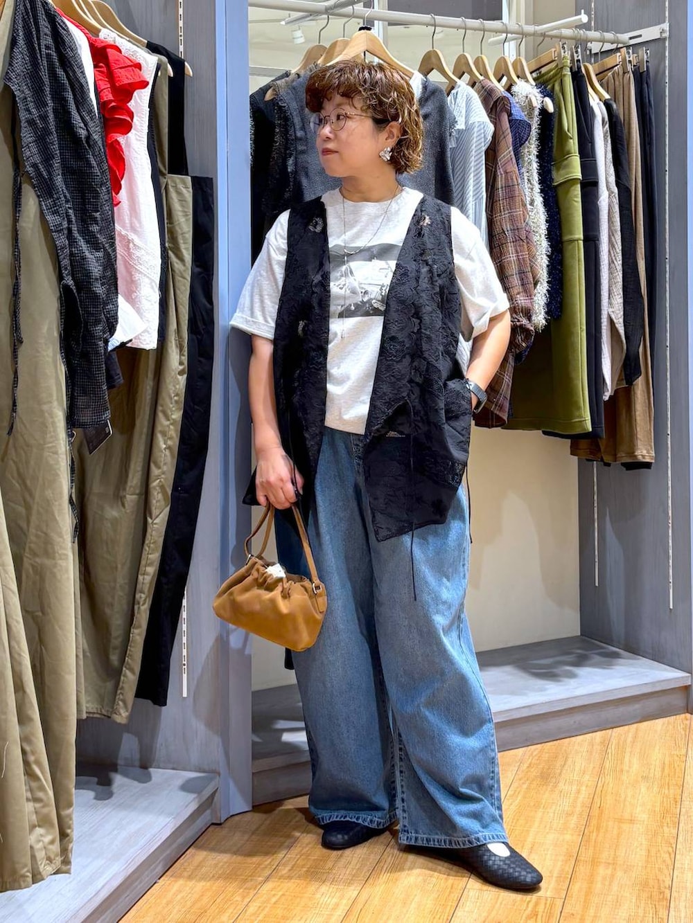 ブルー系のデニムパンツ、ブラウン系のショルダーバッグ、ブラック系のパンプスを着用したレディースの秋コーディネートの2枚目の写真