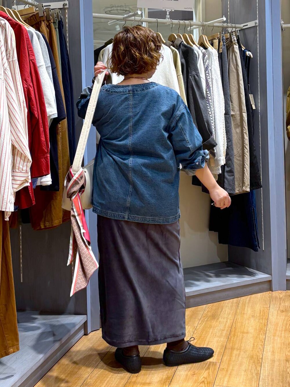 ブルー系のデニムジャケット、ブラック系のパンプス、ベージュ系のショルダーバッグを着用したレディースの秋コーディネートの3枚目の写真