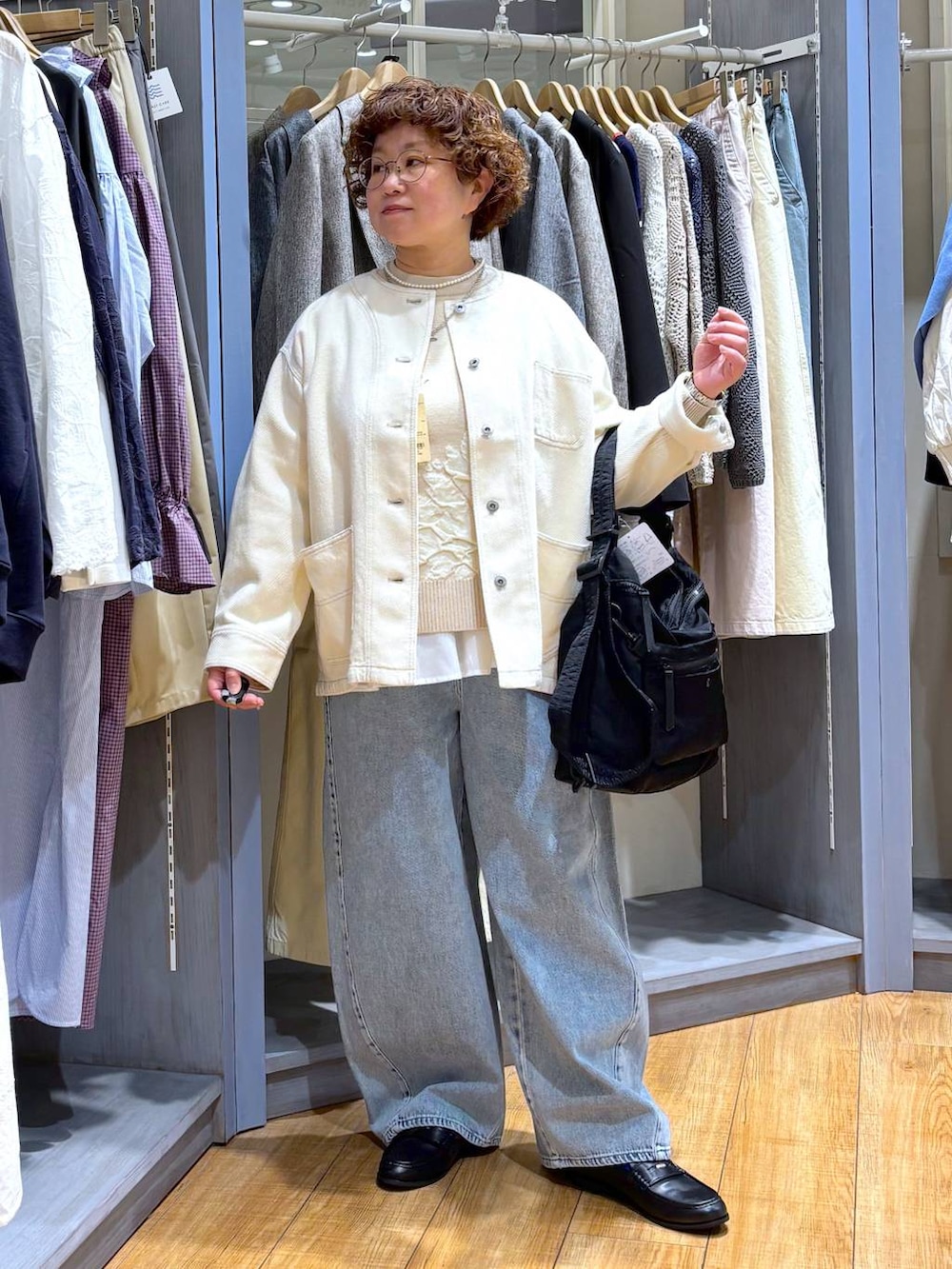 ブルー系のデニムパンツ、ベージュ系のノーカラージャケット、ベージュ系のニット/セーターを着用したレディースの冬コーディネートの2枚目の写真