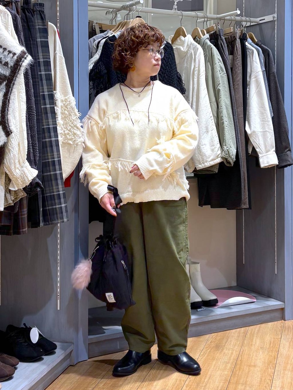 グリーン系のその他パンツ、ブラック系のブーツ、ブラック系のショルダーバッグを着用したレディースの秋コーディネートの2枚目の写真