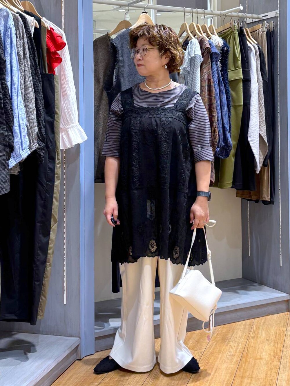 ホワイト系のショルダーバッグ、ブラック系のチュニック、ブラック系のパンプスを着用したレディースの夏コーディネートの2枚目の写真