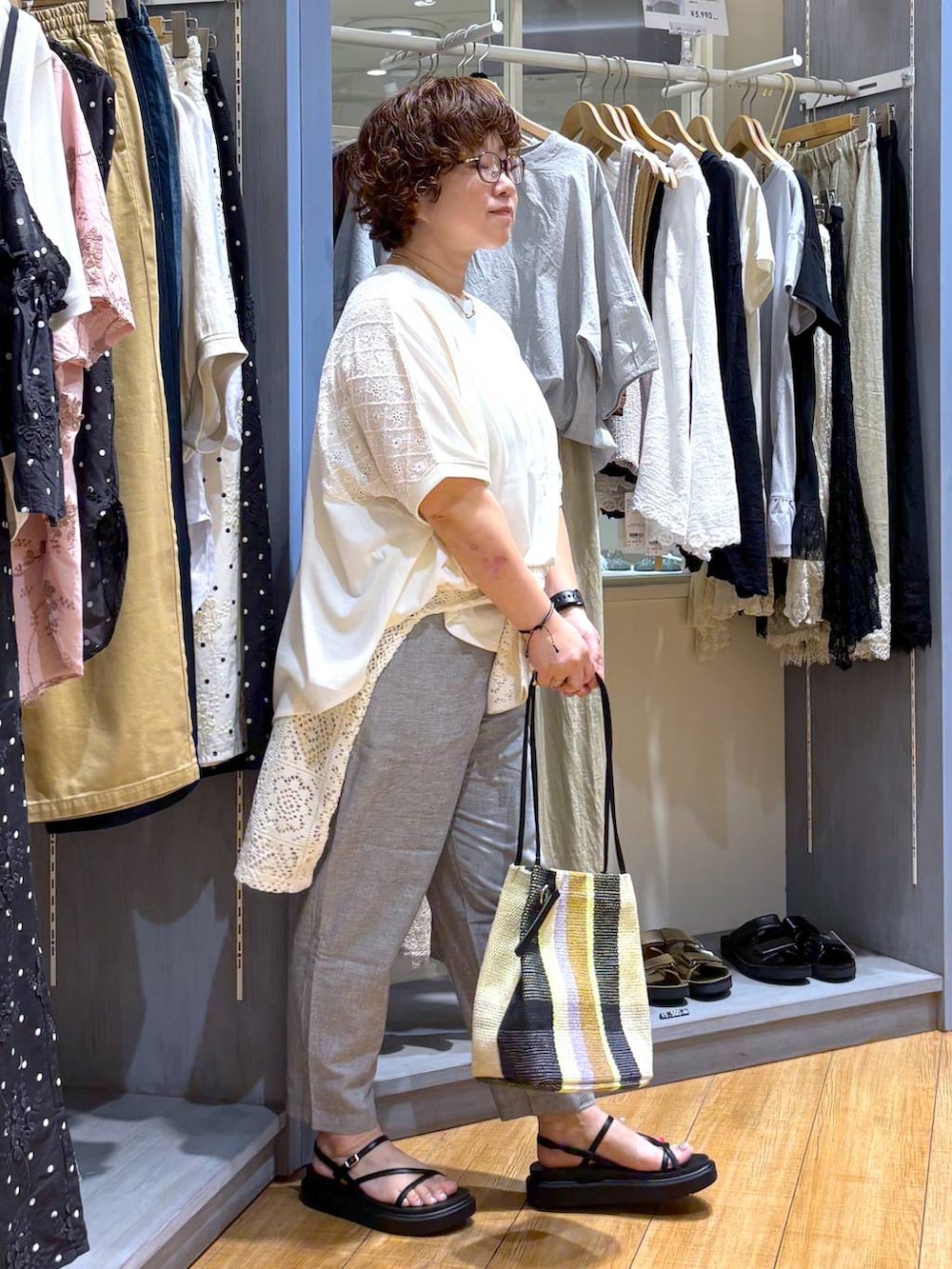 ホワイト系のTシャツ/カットソー、イエロー系のトートバッグ、ブラック系のサンダルを着用したレディースの夏コーディネートの3枚目の写真