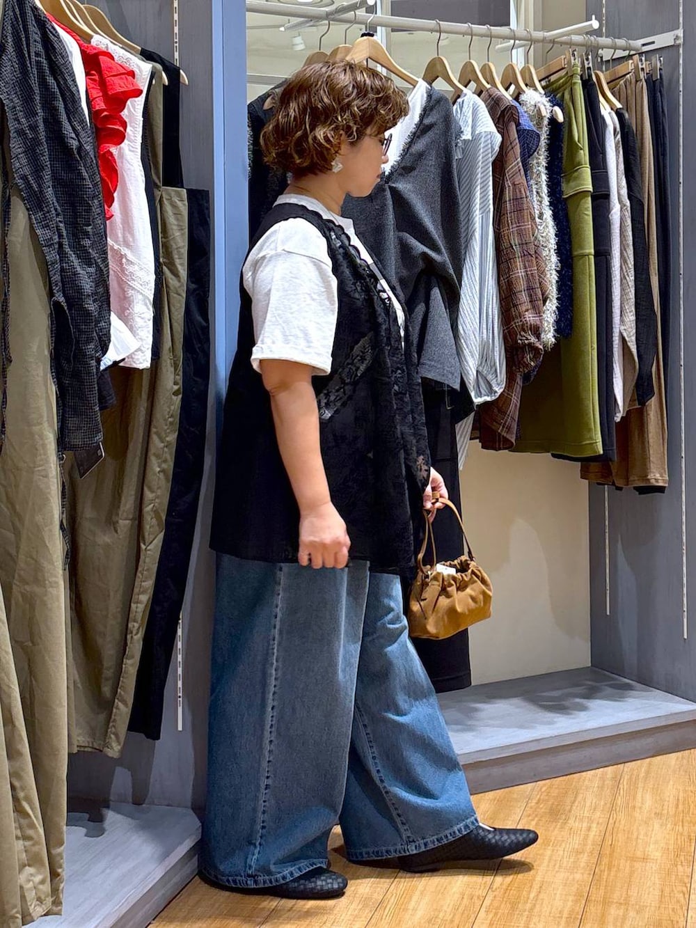 ブルー系のデニムパンツ、ブラウン系のショルダーバッグ、ブラック系のパンプスを着用したレディースの秋コーディネートの4枚目の写真