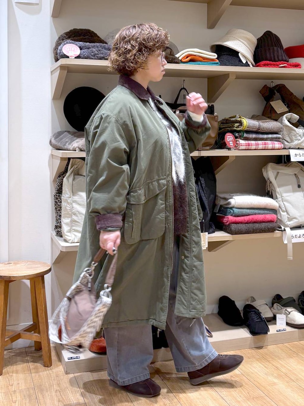 グレー系のデニムパンツ、グリーン系のモッズコート、ブラウン系のショルダーバッグを着用したレディースの秋コーディネートの4枚目の写真