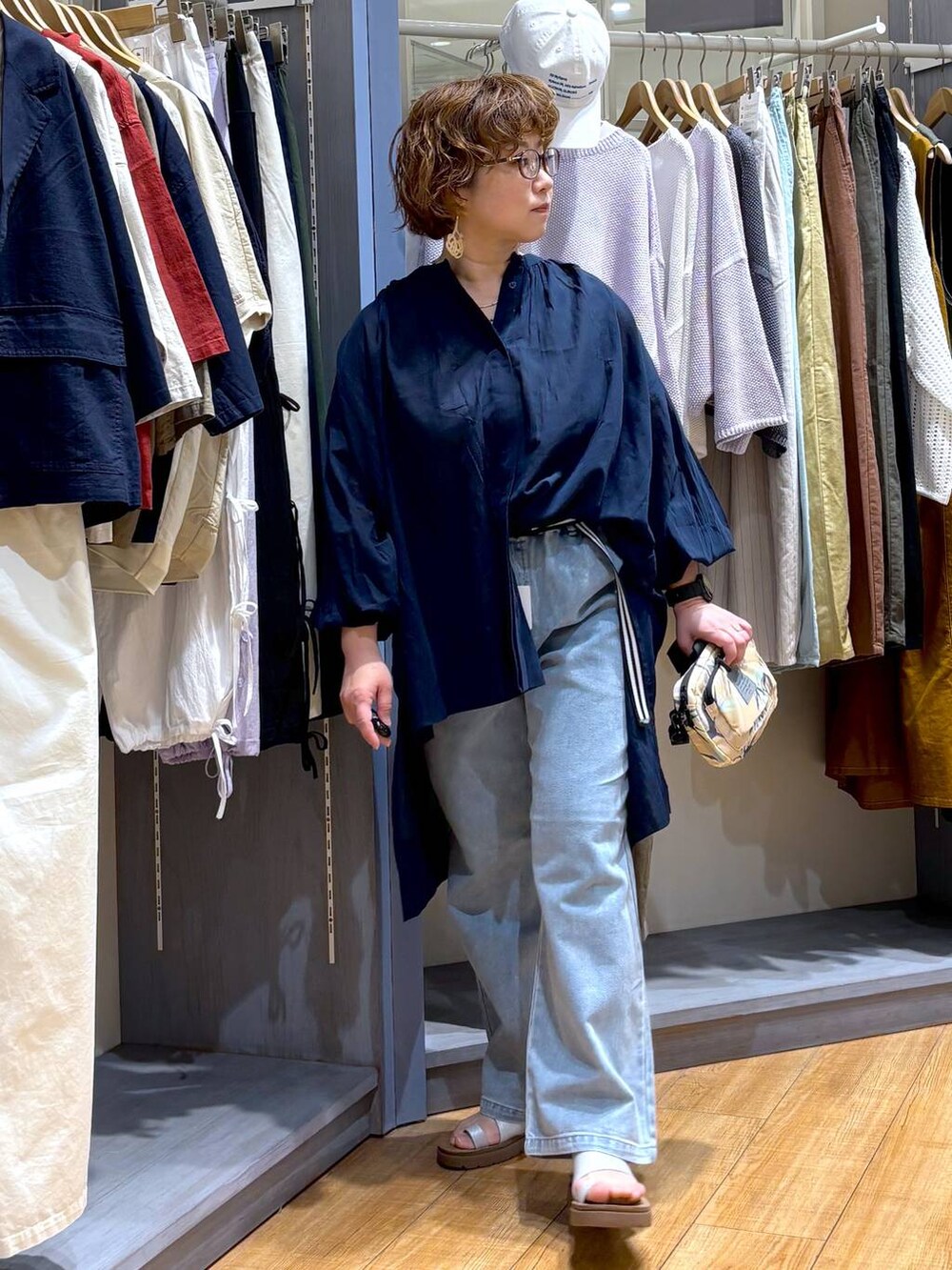その他のサンダル、ブルー系のデニムパンツ、ベージュ系のショルダーバッグを着用したレディースの春コーディネートの2枚目の写真