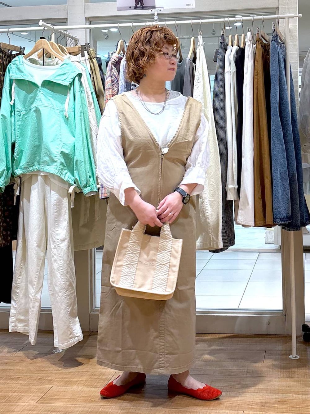 ベージュ系のジャンパースカート、ホワイト系のシャツ/ブラウス、グリーン系のタンクトップを着用したレディースの春コーディネートの5枚目の写真