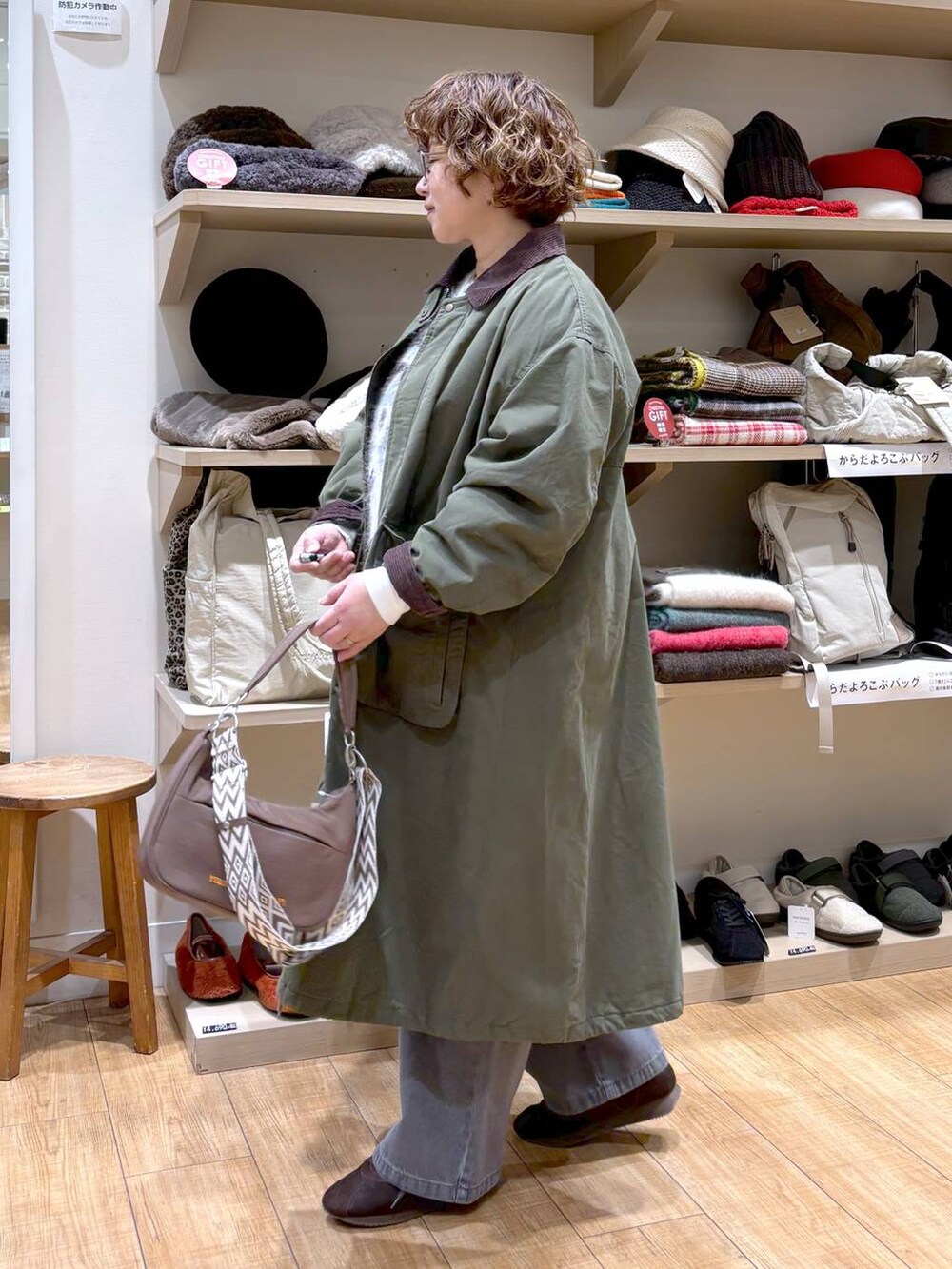 グレー系のデニムパンツ、グリーン系のモッズコート、ブラウン系のショルダーバッグを着用したレディースの秋コーディネートの5枚目の写真