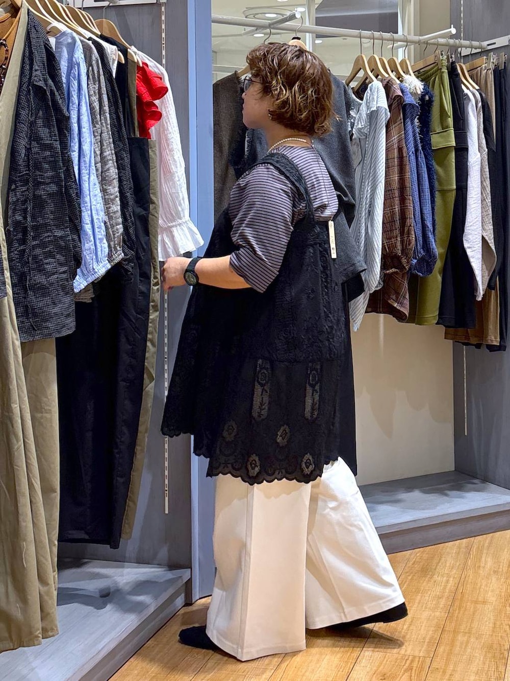 ホワイト系のショルダーバッグ、ブラック系のチュニック、ブラック系のパンプスを着用したレディースの夏コーディネートの4枚目の写真