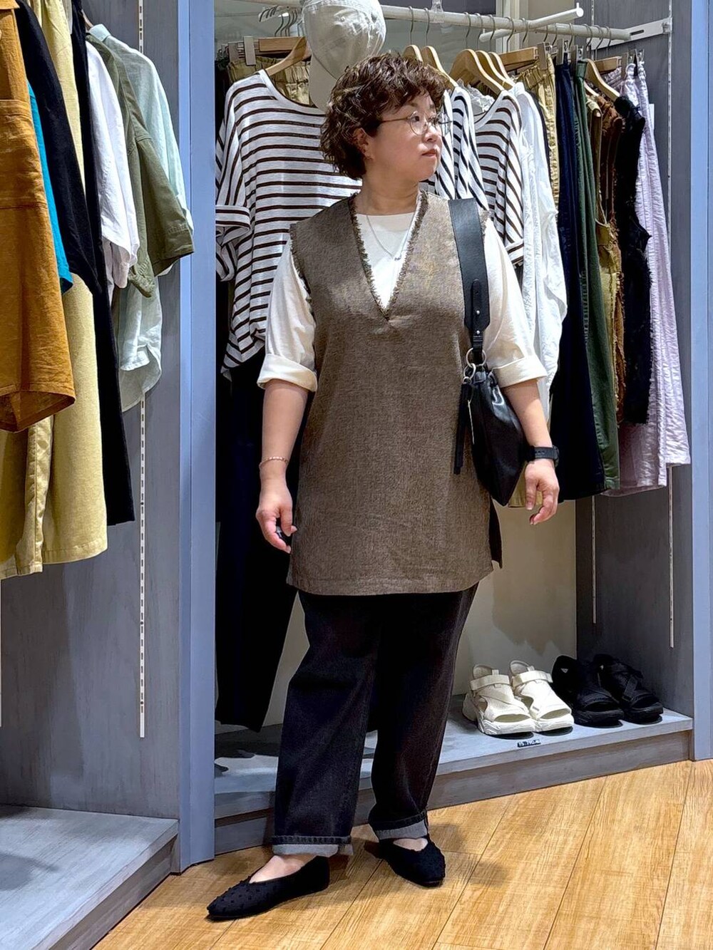 ブラック系のデニムパンツ、ブラウン系のワンピース、ブラック系のショルダーバッグを着用したレディースの夏コーディネートの2枚目の写真