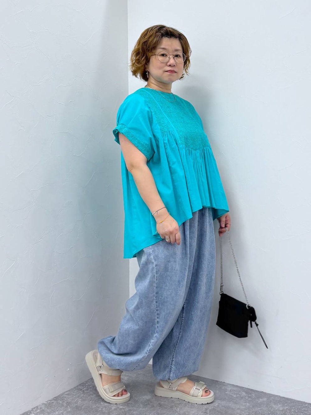 ホワイト系のサンダル、ブルー系のデニムパンツ、その他のネックレスを着用したレディースの夏コーディネートの3枚目の写真