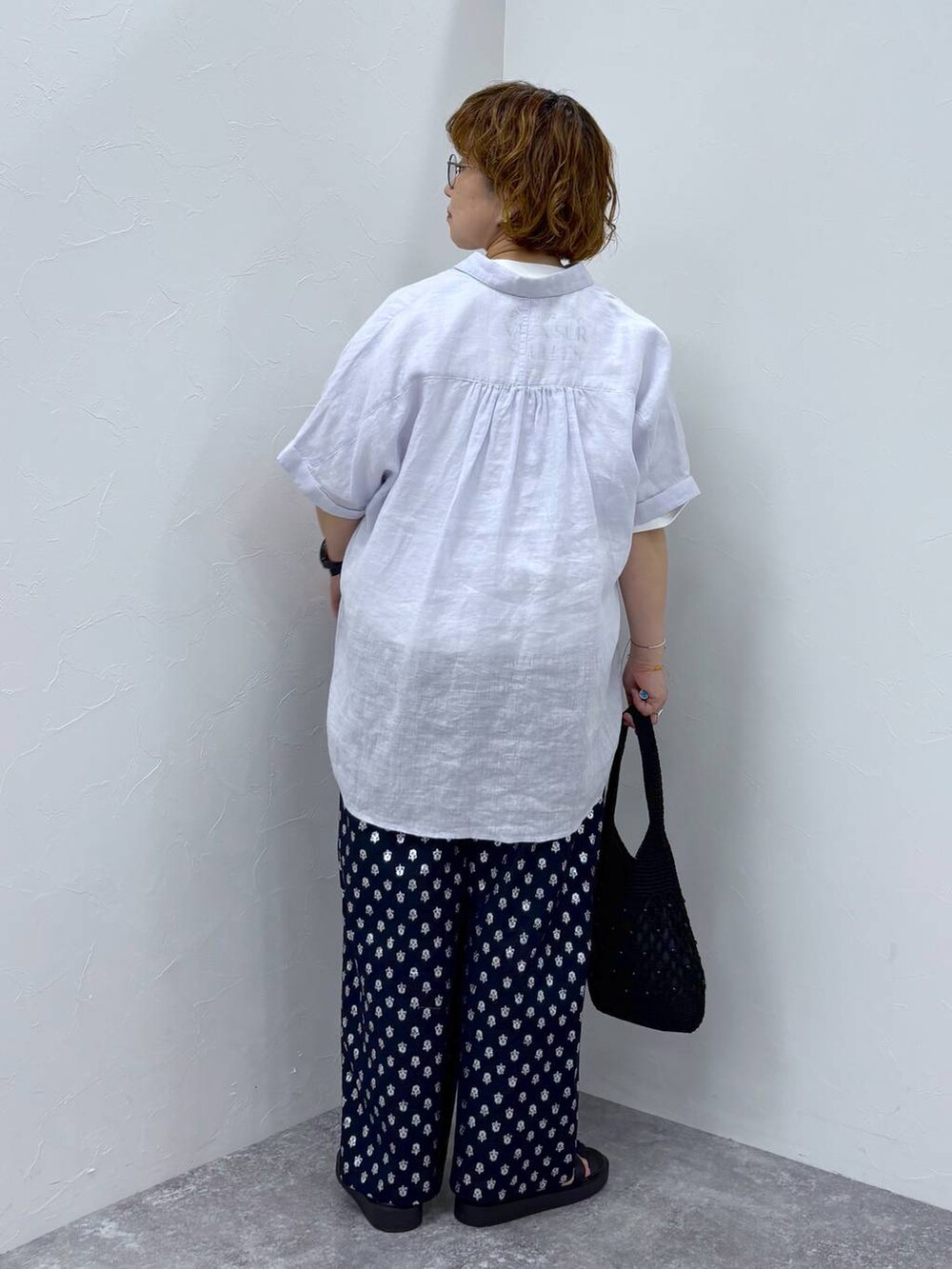 ホワイト系のTシャツ/カットソー、ブラック系のトートバッグ、ブラック系のサンダルを着用したレディースの夏コーディネートの4枚目の写真