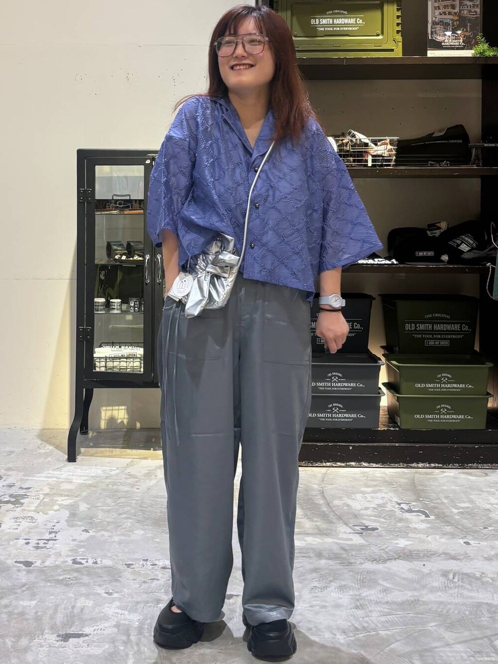 ブラック系のスニーカー、グレー系のショルダーバッグ、ブルー系のシャツ/ブラウスを着用したレディースの夏コーディネートの3枚目の写真