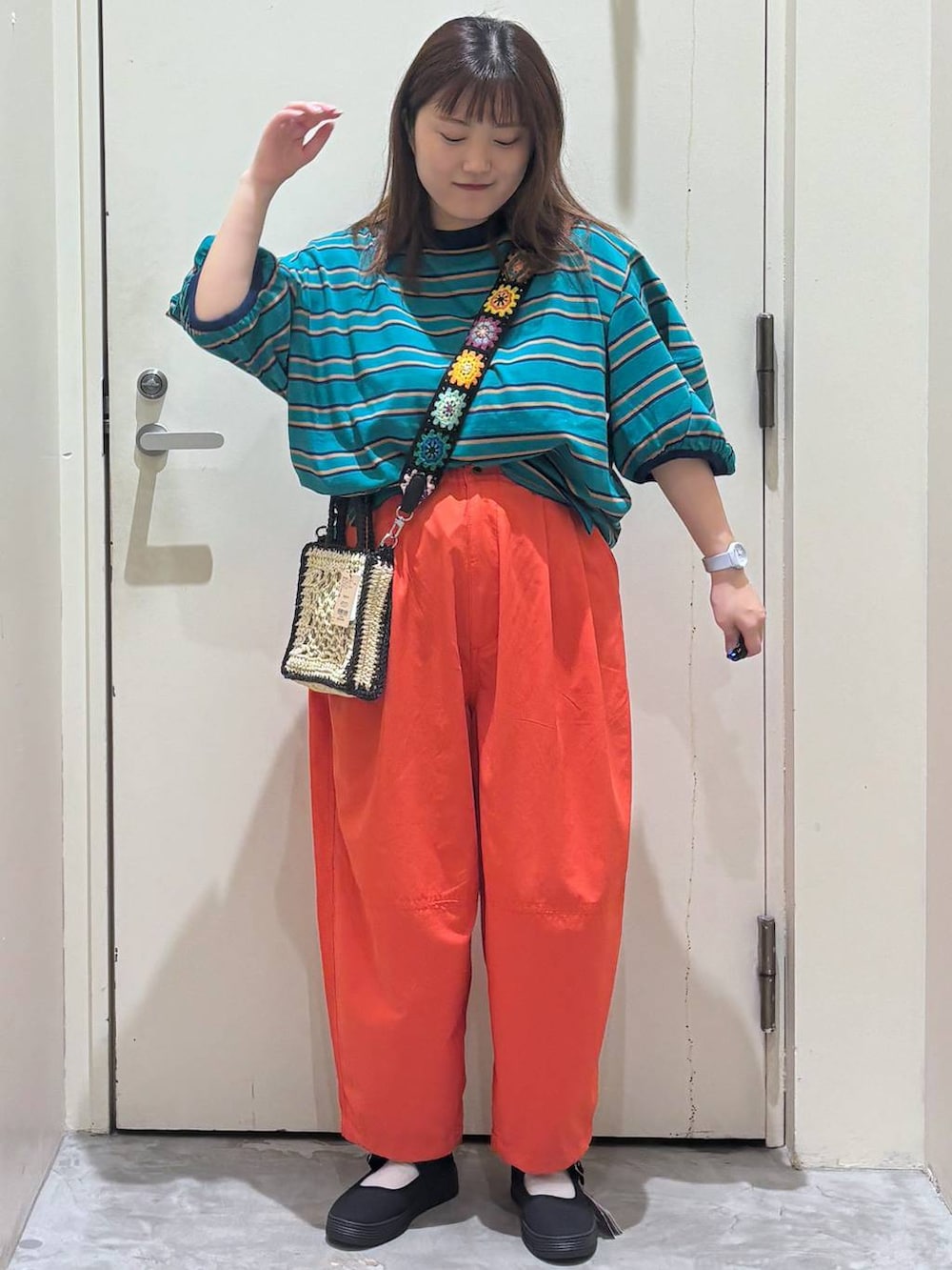 ブラック系のショルダーバッグ、オレンジ系のその他パンツ、グリーン系のTシャツ/カットソーを着用したレディースの夏コーディネートの3枚目の写真