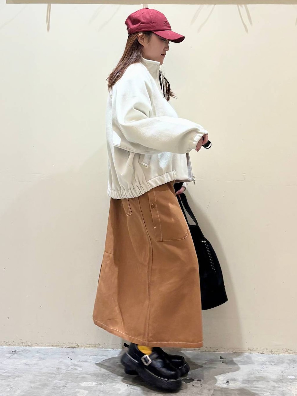 ブラック系のドレスシューズ、ブラウン系のジャンパースカート、ベージュ系のブルゾンを着用したレディースの冬コーディネートの6枚目の写真