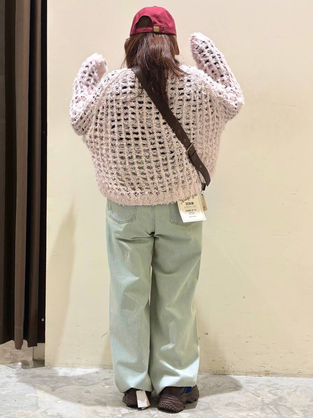 ブラウン系のスニーカー、ブラウン系のショルダーバッグ、ブルー系のデニムパンツを着用したレディースの冬コーディネートの6枚目の写真