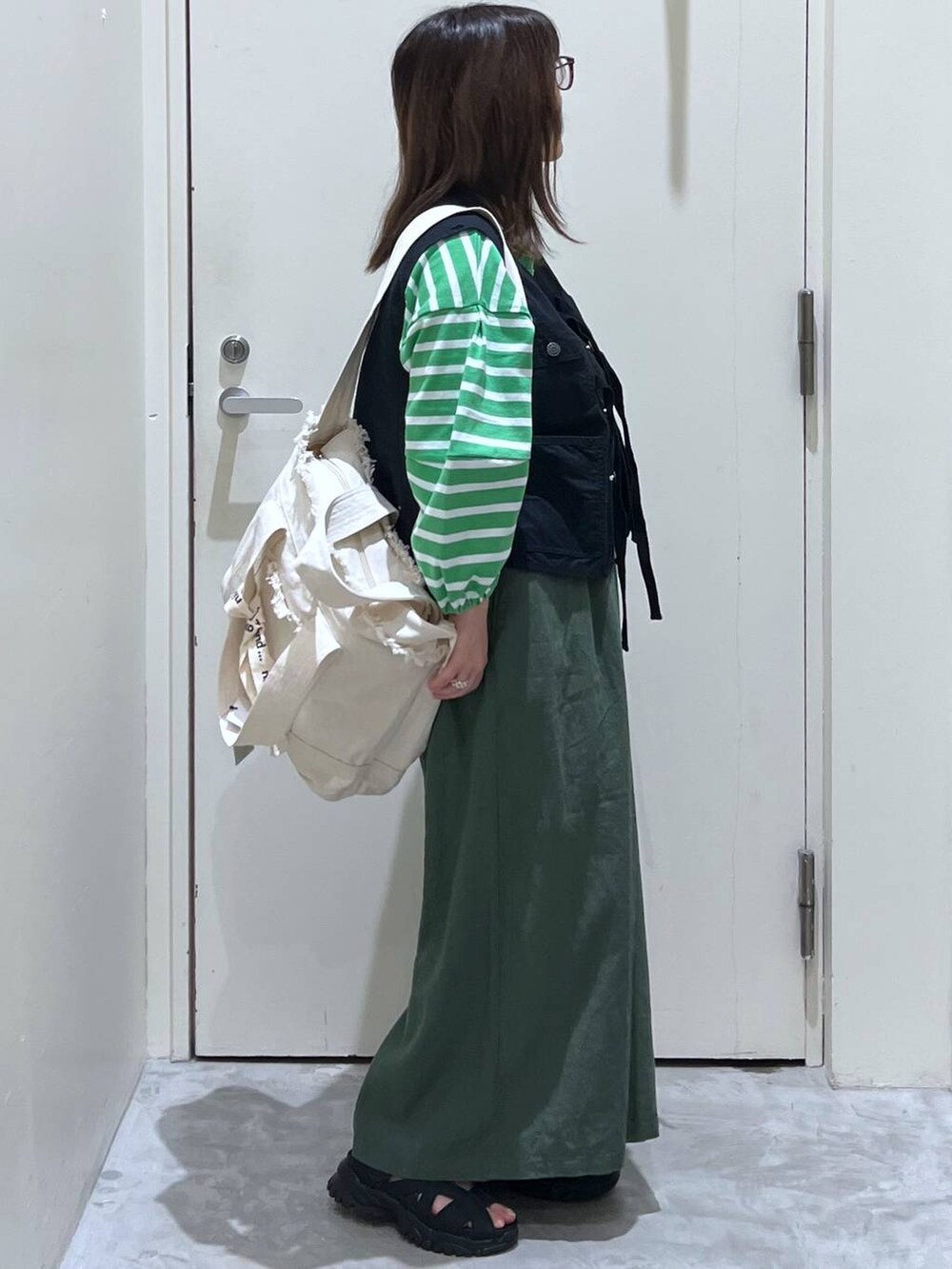 ベージュ系のショルダーバッグ、ブラック系のサンダル、ブラック系のベストを着用したレディースの春コーディネートの5枚目の写真