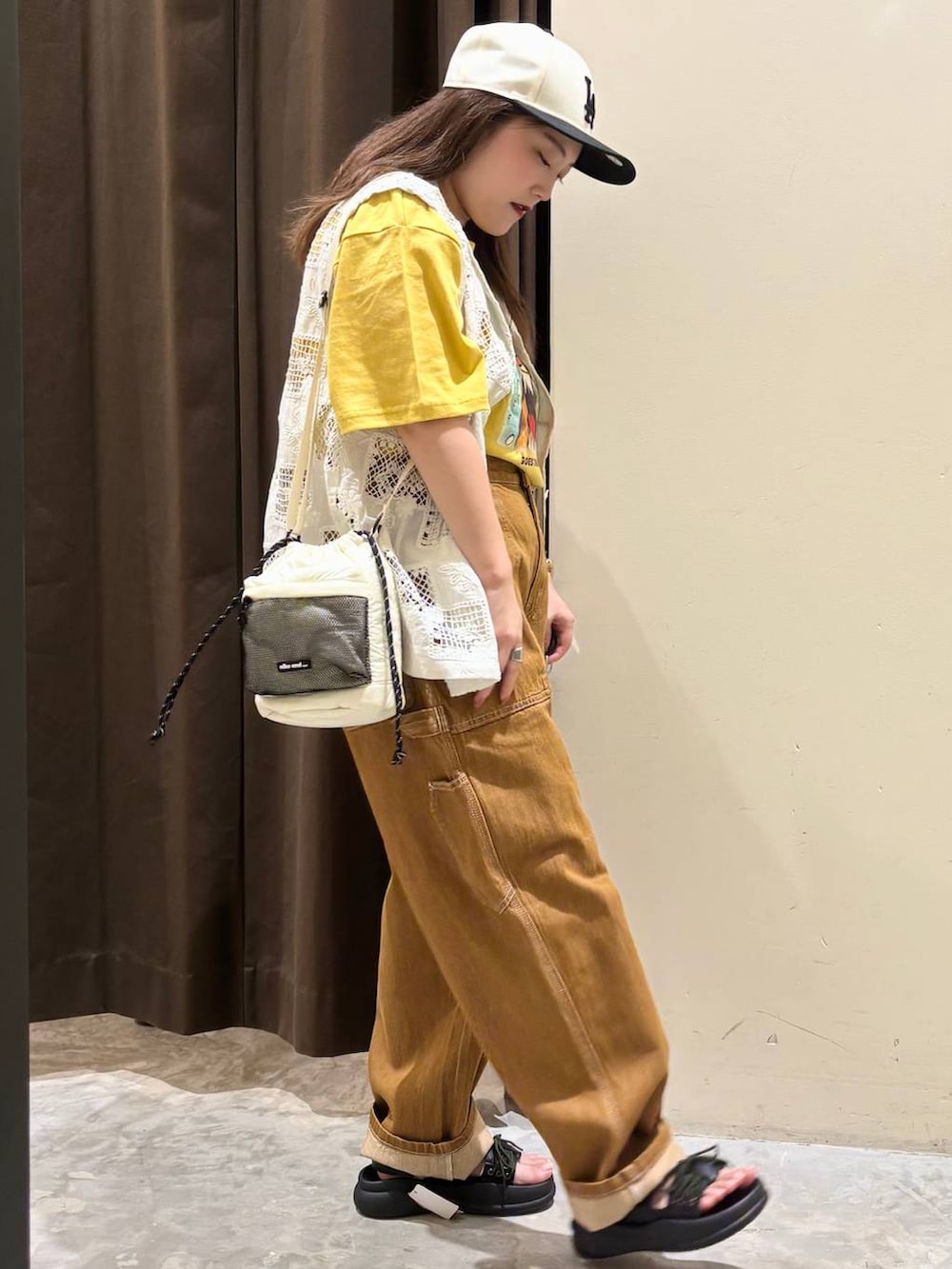 ベージュ系のベスト、ブラウン系のデニムパンツ、ブラック系のサンダルを着用したレディースの夏コーディネートの5枚目の写真