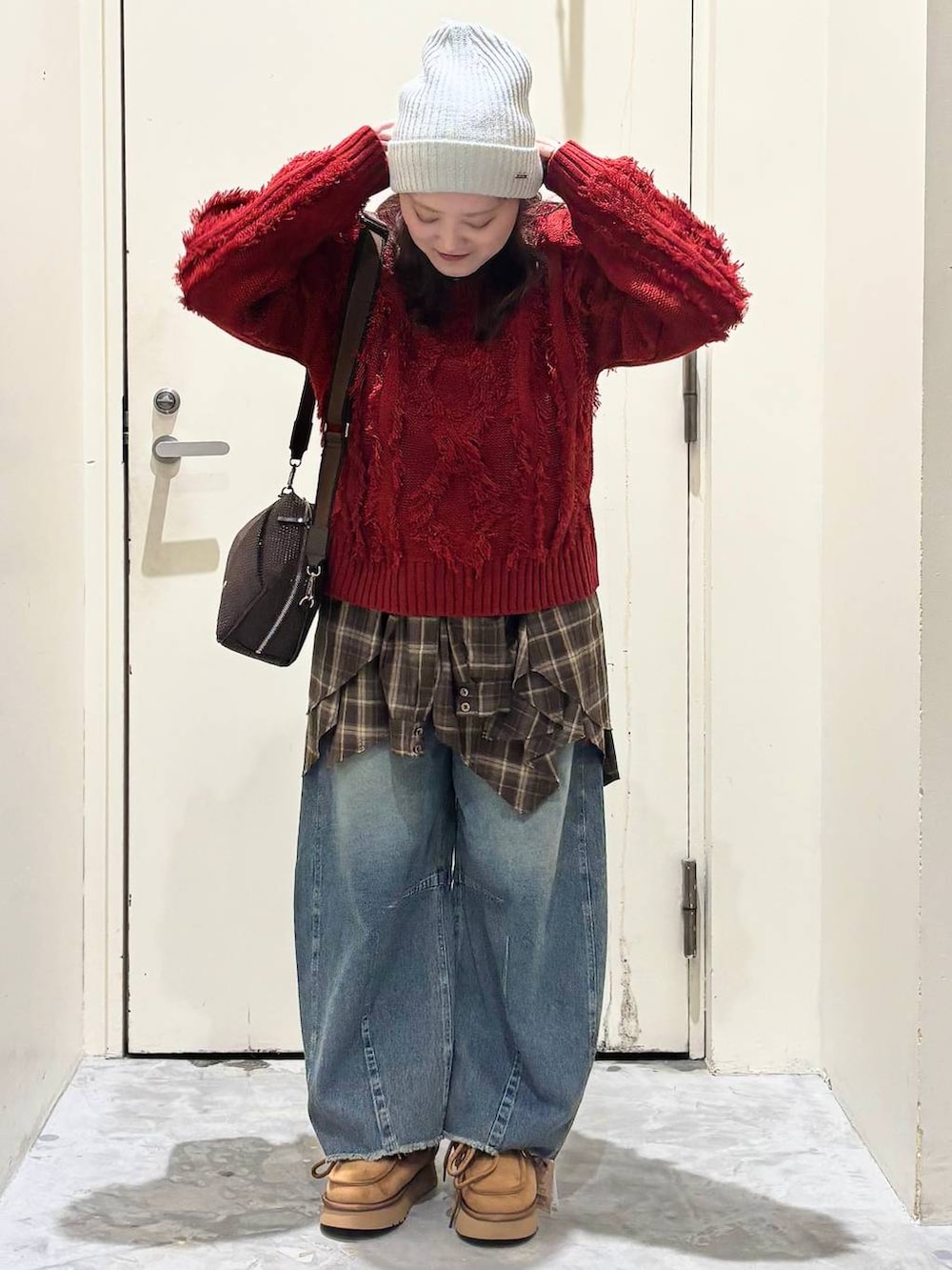 イエロー系のモカシン/デッキシューズ、ブルー系のデニムパンツ、レッド系のニット/セーターを着用したレディースの冬コーディネートの2枚目の写真