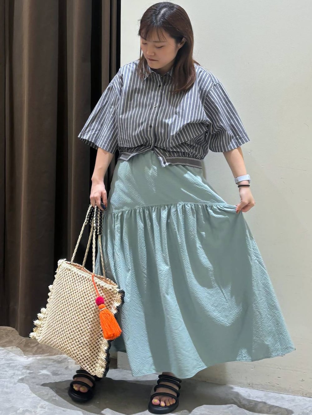 ブラック系のサンダル、グリーン系のスカート、ベージュ系のトートバッグを着用したレディースの夏コーディネートの3枚目の写真