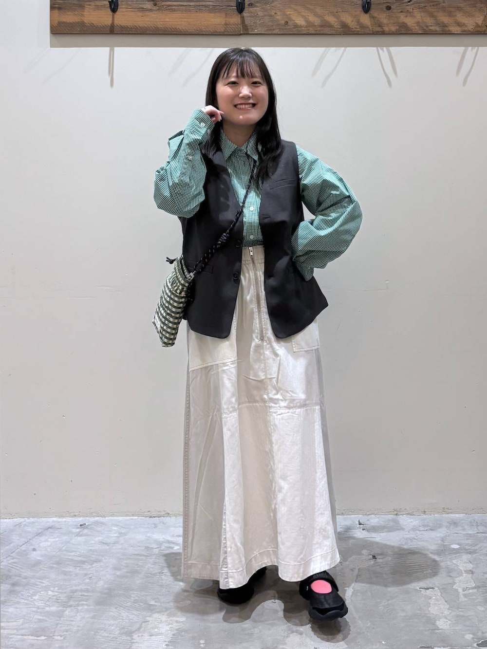 グリーン系のショルダーバッグ、ブラック系のベスト、ブラック系のバレエシューズを着用したレディースの春コーディネートの3枚目の写真