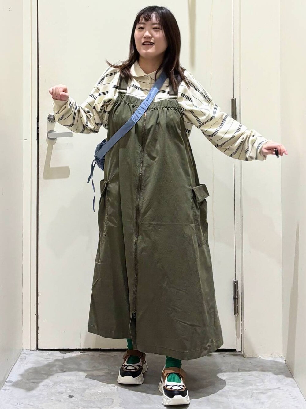 グリーン系のジャンパースカート、その他のスニーカー、ブルー系のショルダーバッグを着用したレディースの冬コーディネートの5枚目の写真