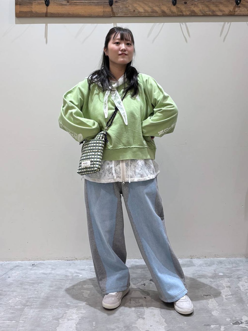 グレー系のデニムパンツ、グリーン系のショルダーバッグ、ホワイト系のベストを着用したレディースの春コーディネートの2枚目の写真