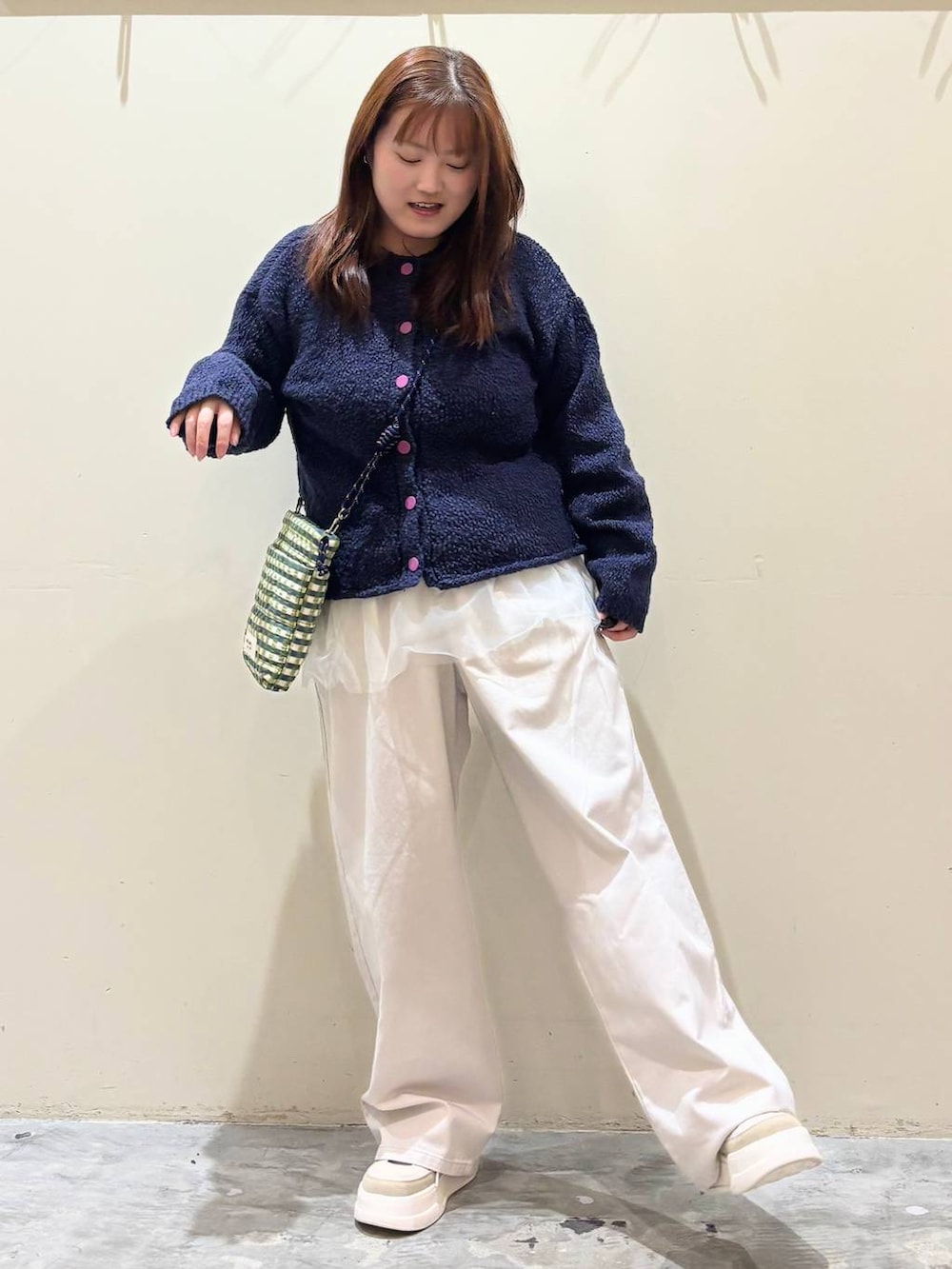 グリーン系のショルダーバッグ、ブルー系のニット/セーター、ベージュ系のチノパンツを着用したレディースの冬コーディネートの4枚目の写真