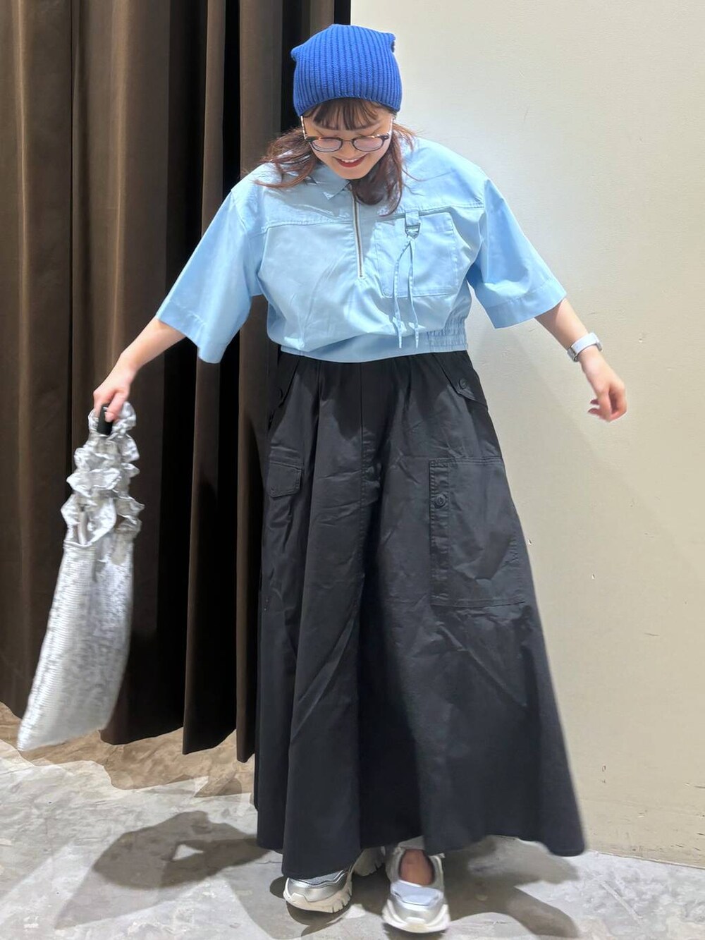 シルバー系のトートバッグ、シルバー系のスニーカー、グレー系のスカートを着用したレディースの夏コーディネートの2枚目の写真