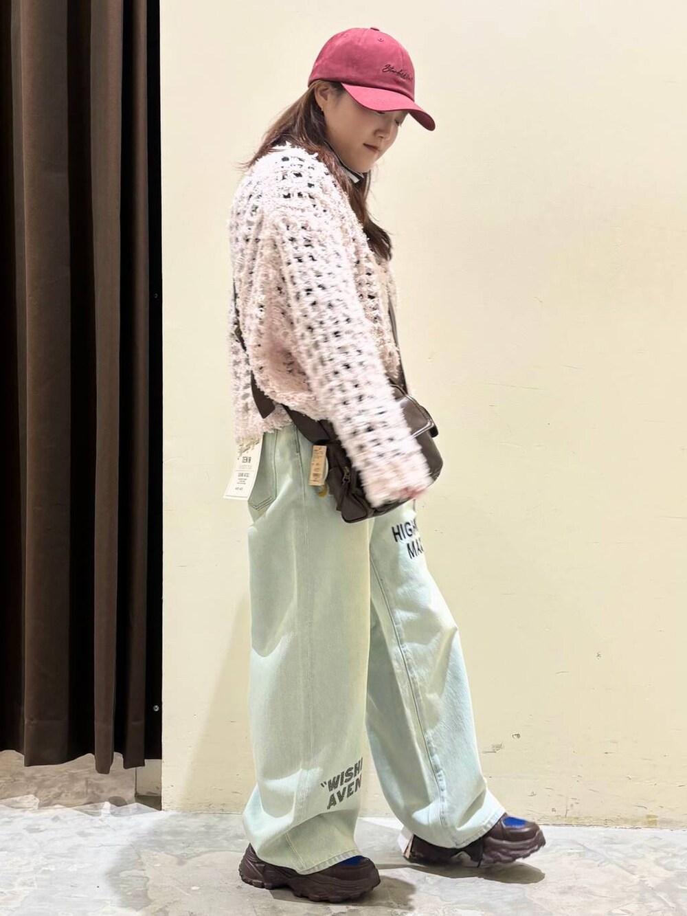 ブラウン系のスニーカー、ブラウン系のショルダーバッグ、ブルー系のデニムパンツを着用したレディースの冬コーディネートの5枚目の写真