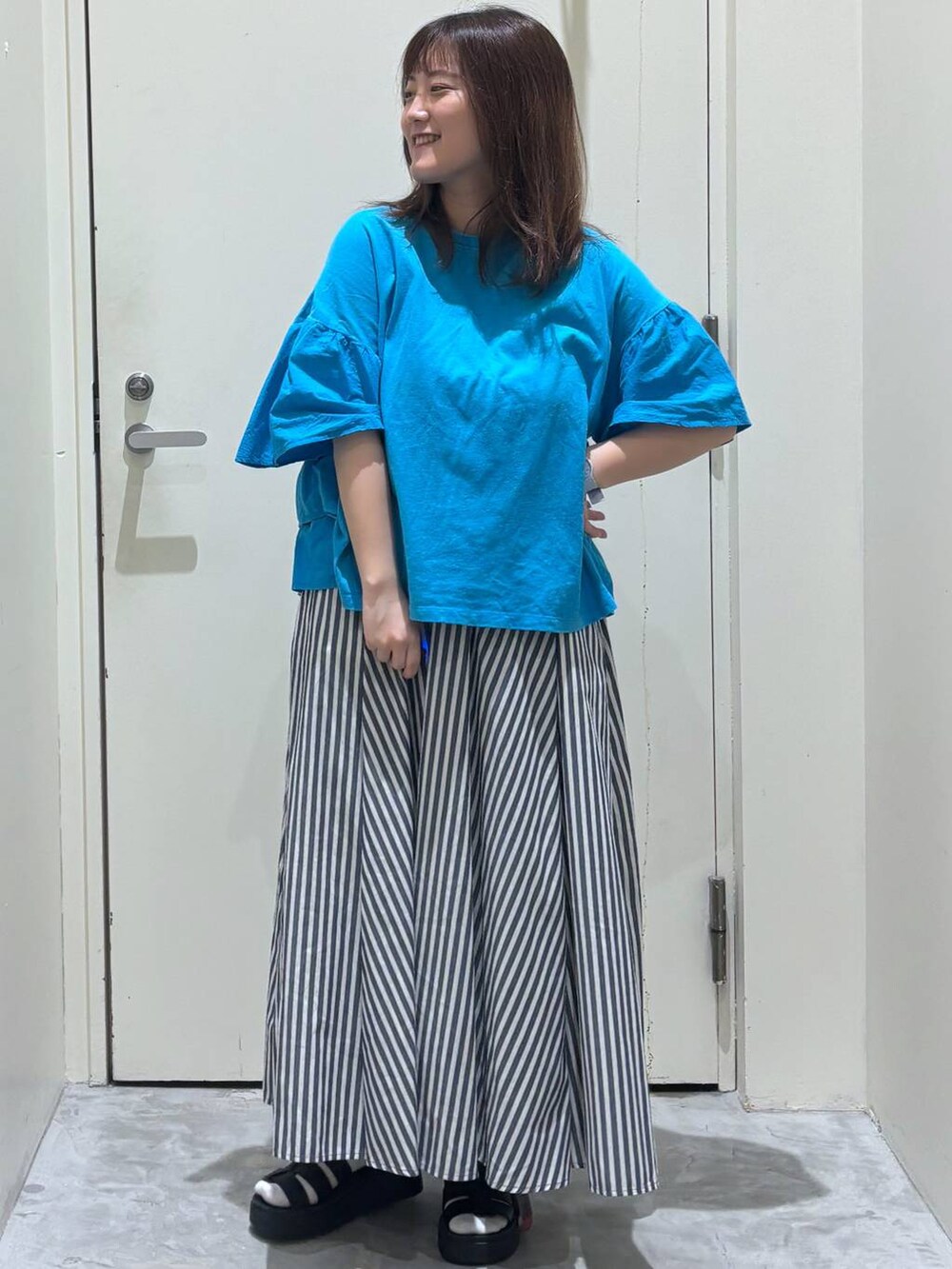 ブラック系のサンダル、ブルー系のスカート、ブルー系のTシャツ/カットソーを着用したレディースの夏コーディネートの2枚目の写真