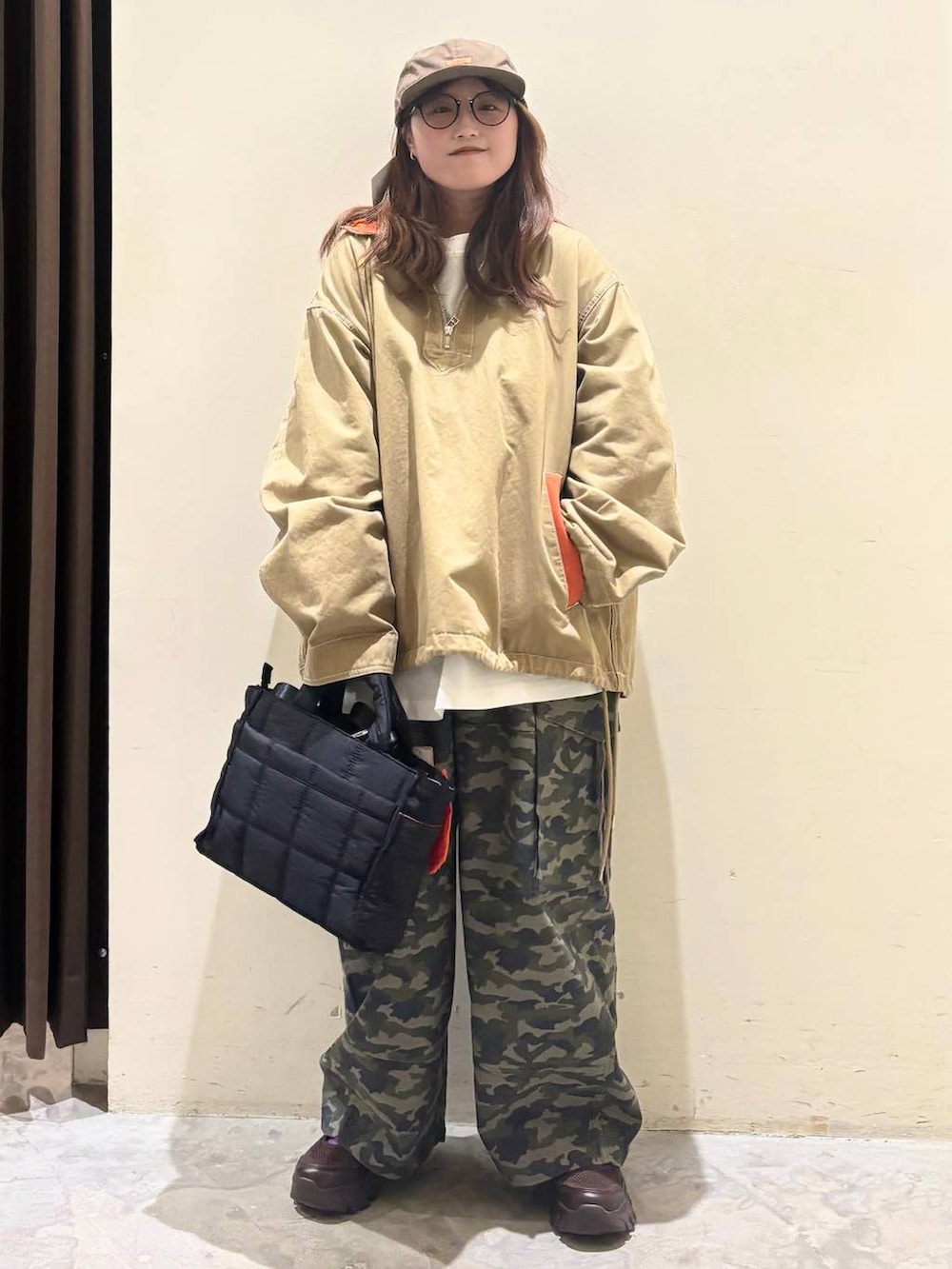 ブラック系のトートバッグ、ブラウン系のスニーカー、ベージュ系のパーカーを着用したレディースの春コーディネートの3枚目の写真