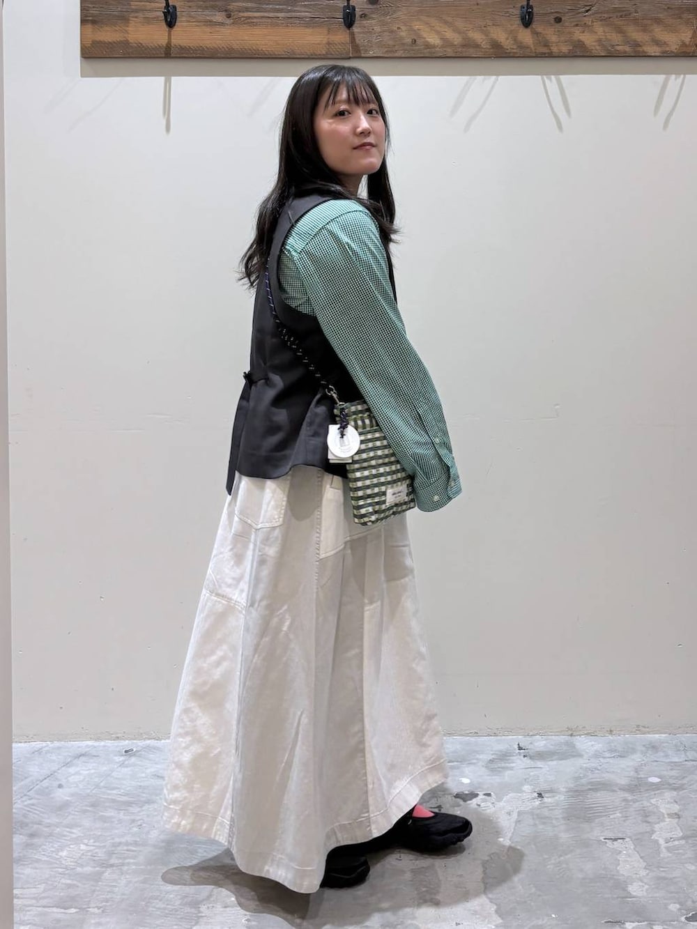 グリーン系のショルダーバッグ、ブラック系のベスト、ブラック系のバレエシューズを着用したレディースの春コーディネートの6枚目の写真