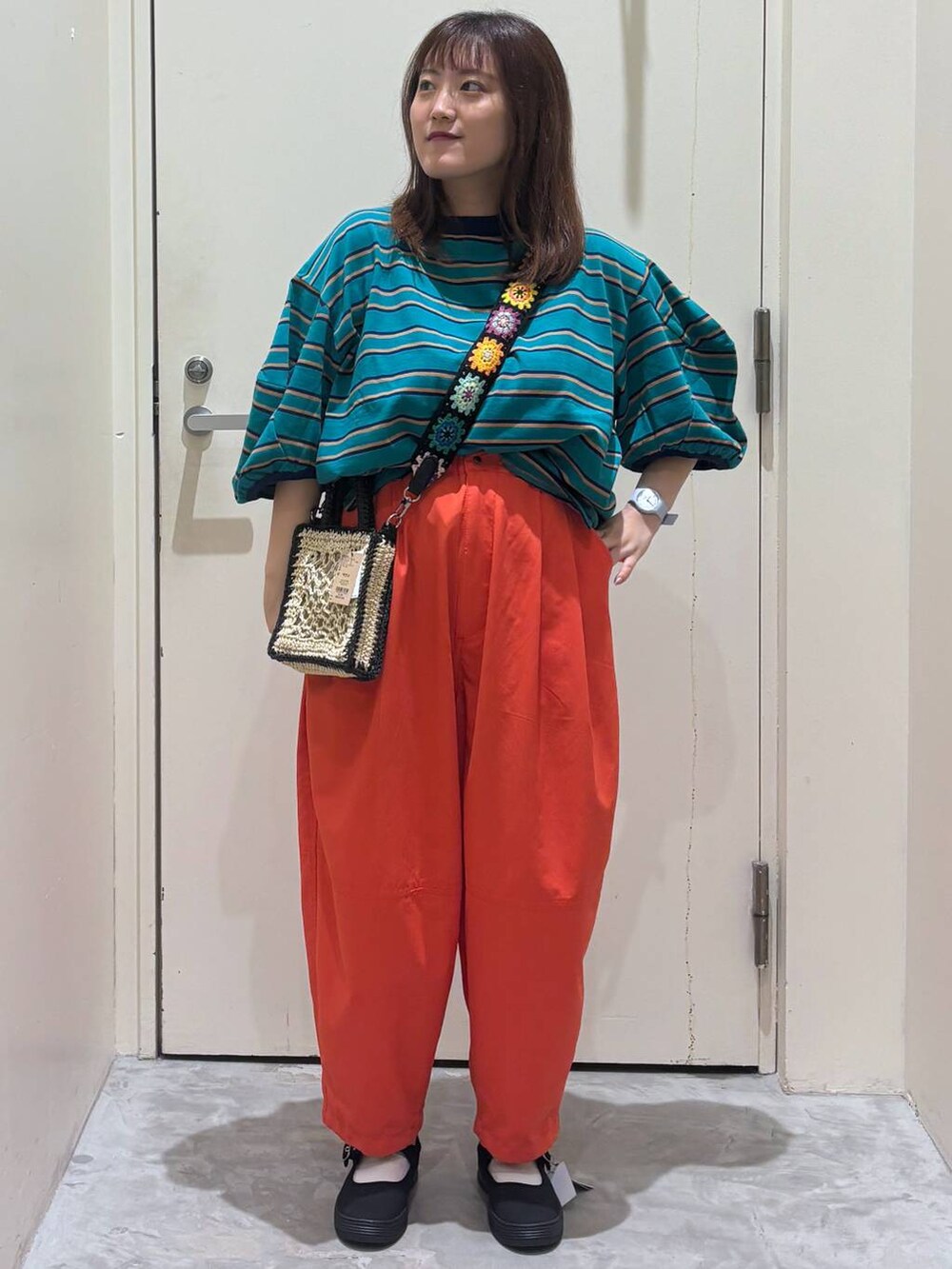 ブラック系のショルダーバッグ、オレンジ系のその他パンツ、グリーン系のTシャツ/カットソーを着用したレディースの夏コーディネートの4枚目の写真