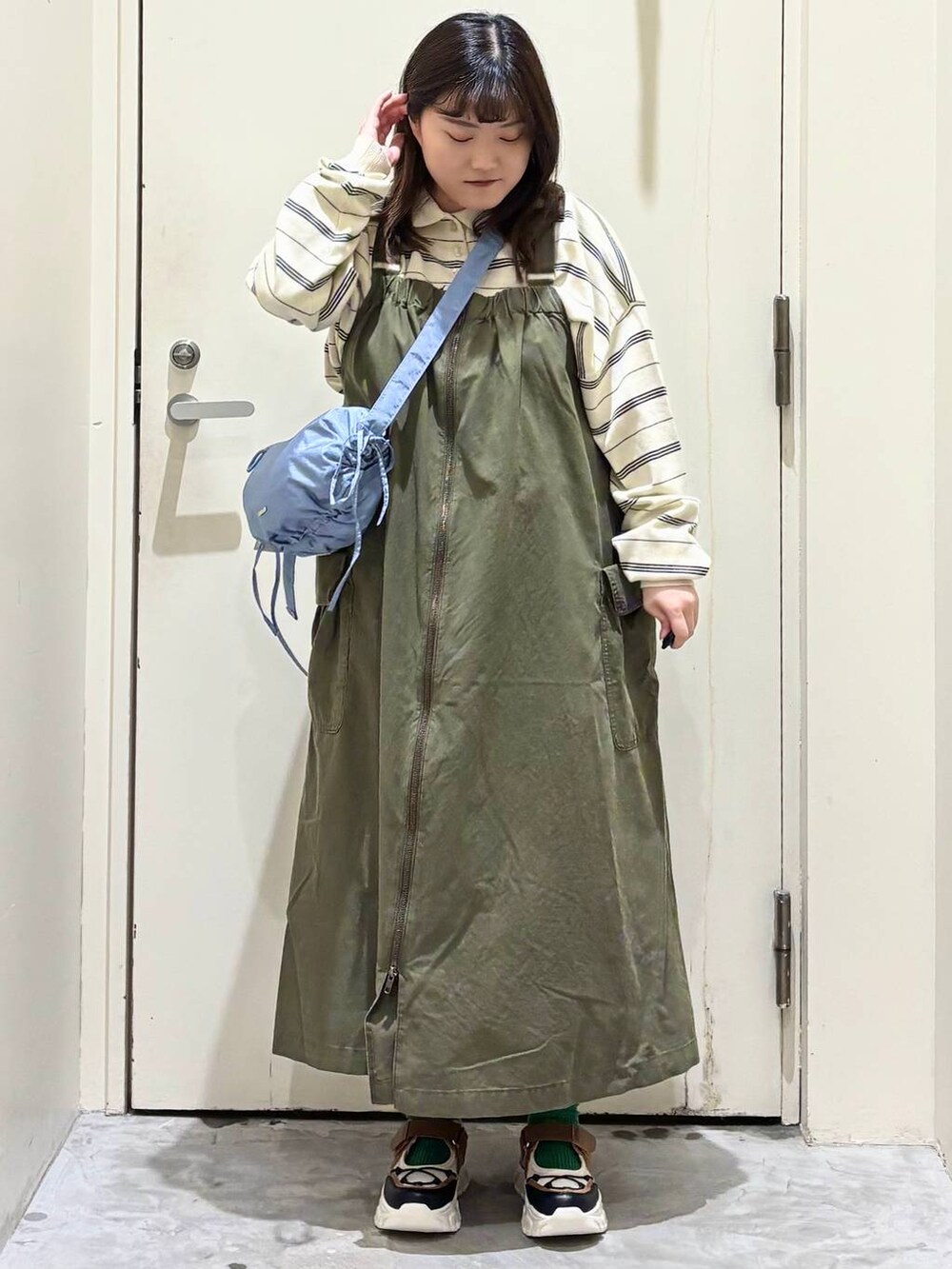 グリーン系のジャンパースカート、その他のスニーカー、ブルー系のショルダーバッグを着用したレディースの冬コーディネートの4枚目の写真