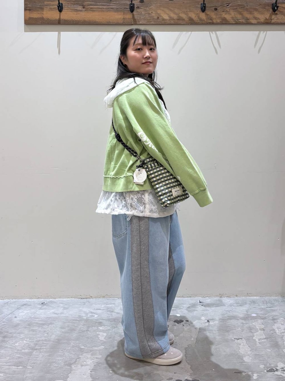 グレー系のデニムパンツ、グリーン系のショルダーバッグ、ホワイト系のベストを着用したレディースの春コーディネートの3枚目の写真