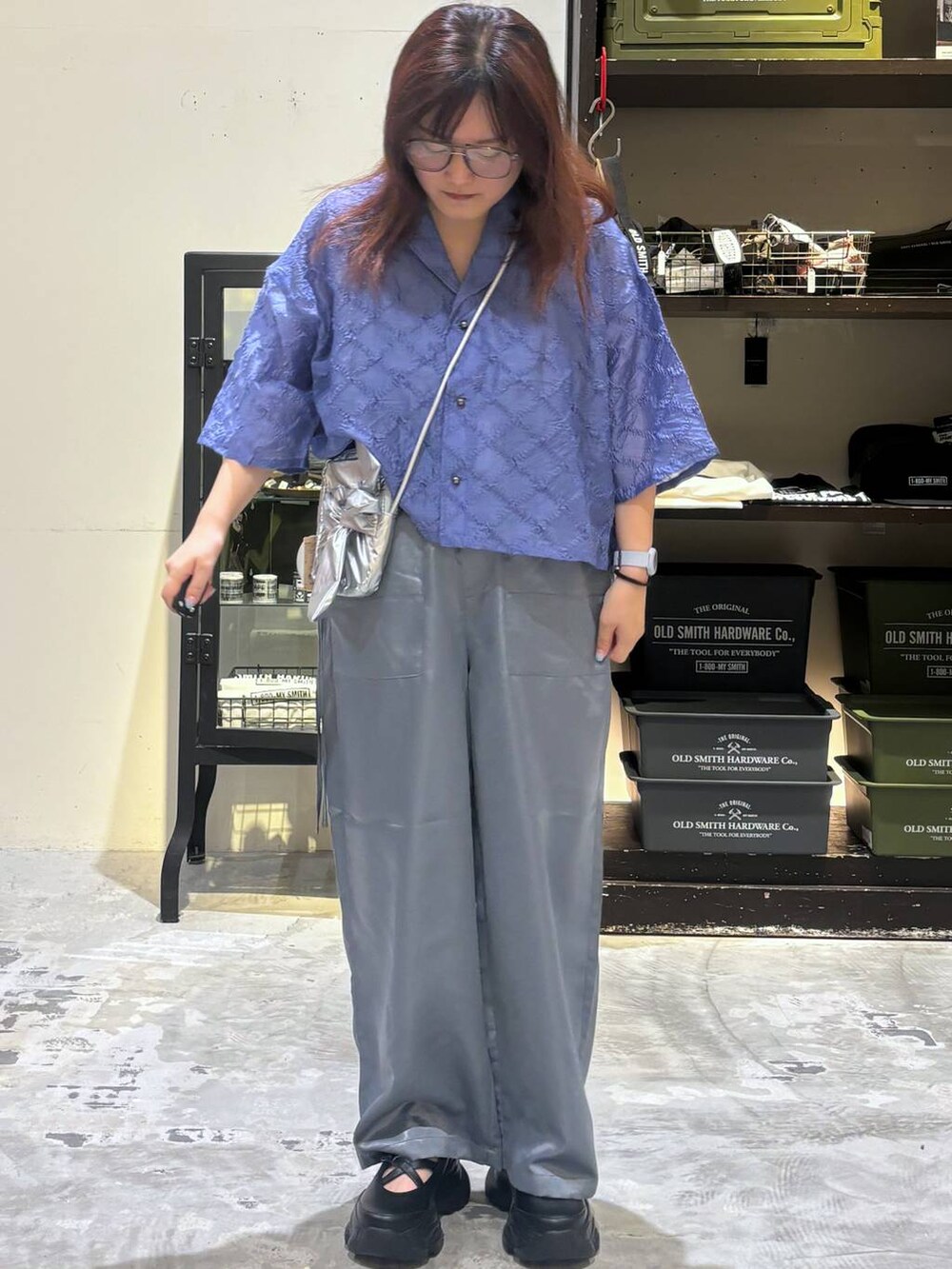 ブラック系のスニーカー、グレー系のショルダーバッグ、ブルー系のシャツ/ブラウスを着用したレディースの夏コーディネートの2枚目の写真